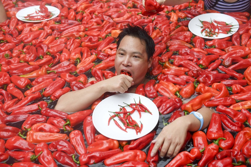  A competitor taking part in a chilli pepper eating contest in a hot spring filled with chilli peppers. (STR / AFP)