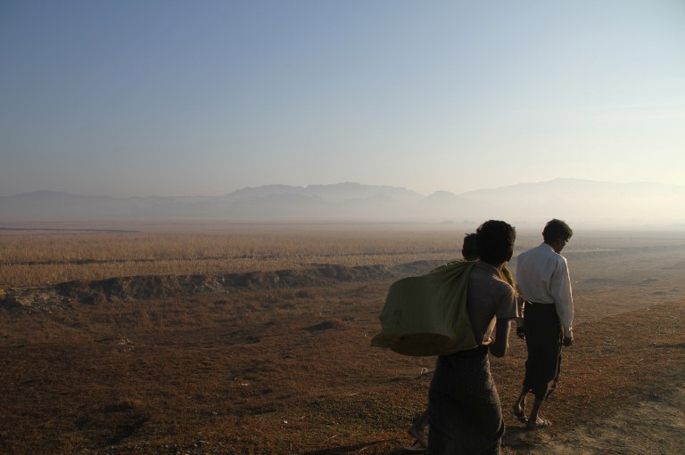 Three people walking along a road are seen during a government-organized visit for journalists in Buthidaung townships close to the surge of fighting between the Arakan Army and government troops in Rakhine state on January 25, 2019. (Richard Sargent / AFP)