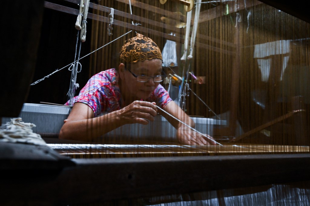  Rampai Sripetch, a 65-year-old Thai Muslim woman, weaves silk fabric on a loom at a workshop near Darul Falah mosque in Bangkok. (Romeo Gacad / AFP)