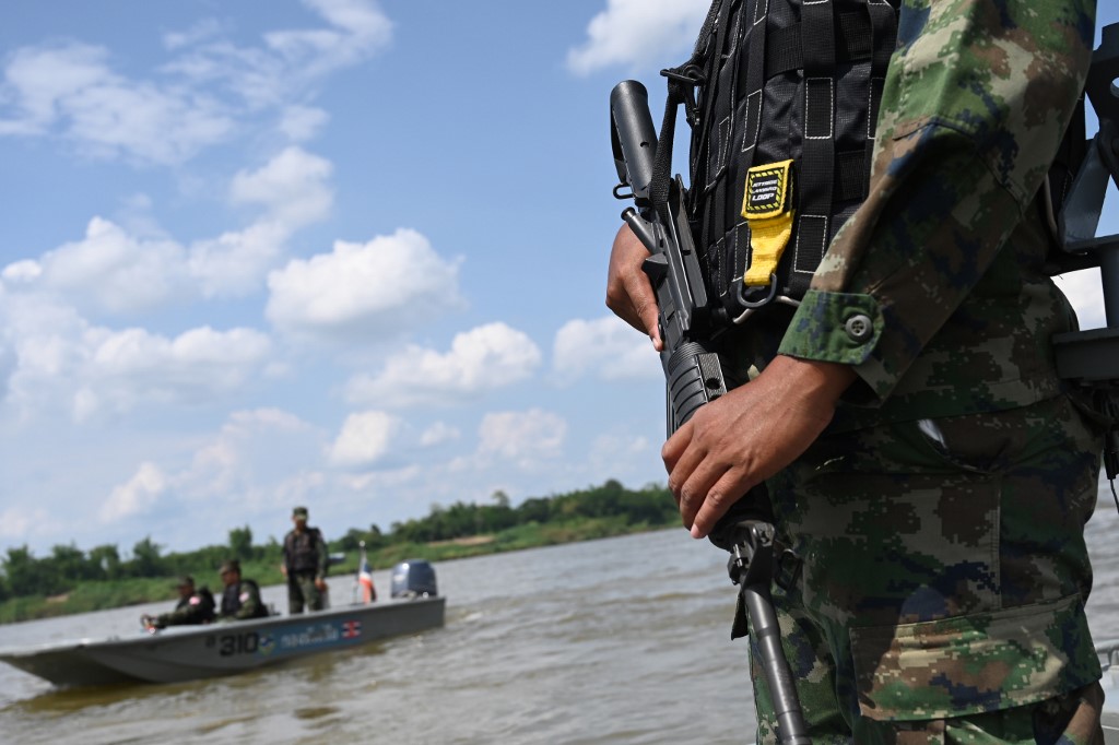 An armed Thai navy personnel riding in a boat during a patrol along the Mekong river bordering Thailand and Laos in Tha Utain, Nakhon Phanom province. (Aidan Jones / AFP)