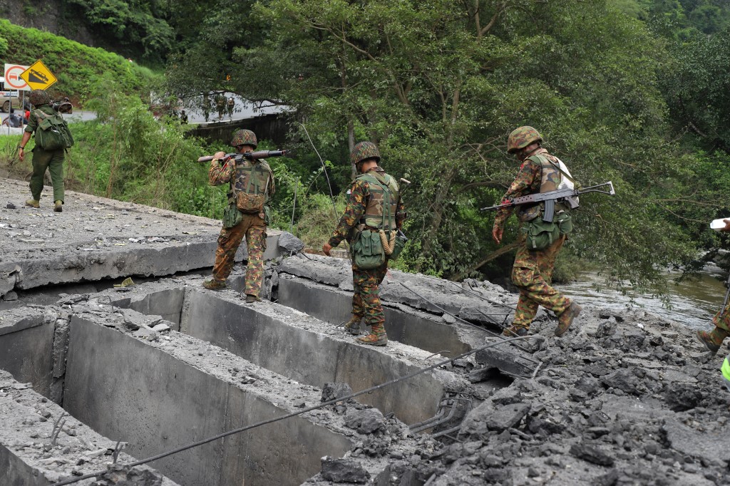  Armed government troops cross a bomb damaged bridge outside the compound of the Gote Twin police station in Shan State on August 15, 2019, after it was attacked by ethnic rebel groups. (STR / AFP)