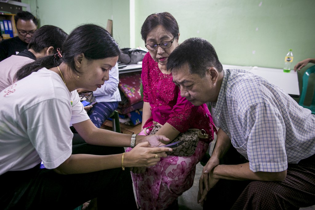  This photograph taken on September 22, 2019 shows Myanmar information technology volunteers assisting mobile phone users switching from the old Zawgyi font to the unicode font in Yangon. (Sai Aung Main / AFP)