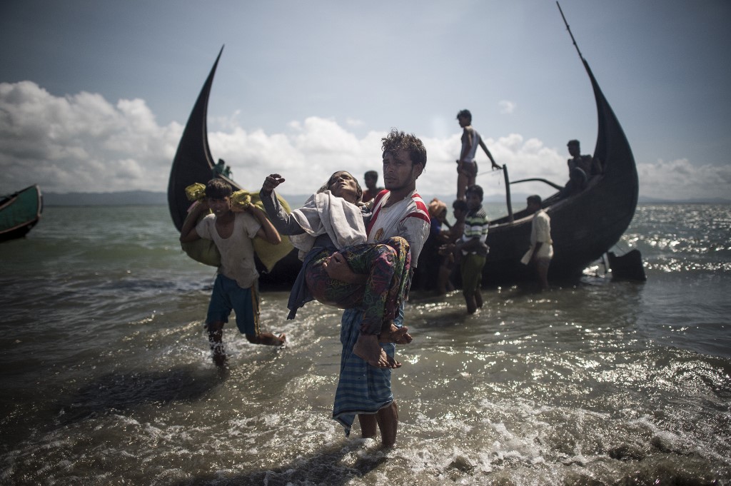 A Bangladeshi man helps Rohingya Muslim refugees to disembark from a boat on the Bangladeshi shoreline of the Naf river after crossing the border from Myanmar in Teknaf on September 30, 2017. (Fred Dufour / AFP)