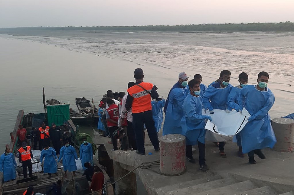 Rescue workers carry a dead body (R) following a boat capsizing accident, in Teknaf on February 11, 2020. (STR / AFP)