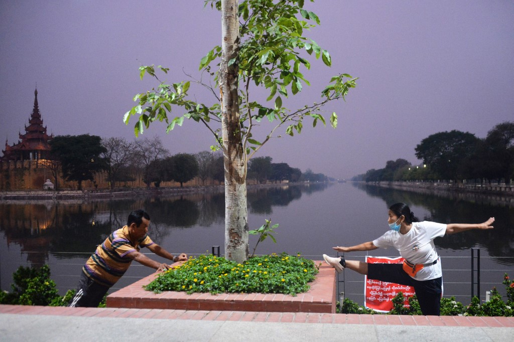 People wearing face masks exercise at dawn in Mandalay on April 7, 2020, as the regional government started a community lockdown to combat the spread of the COVID-19 novel coronavirus. (Thet Aung / AFP)