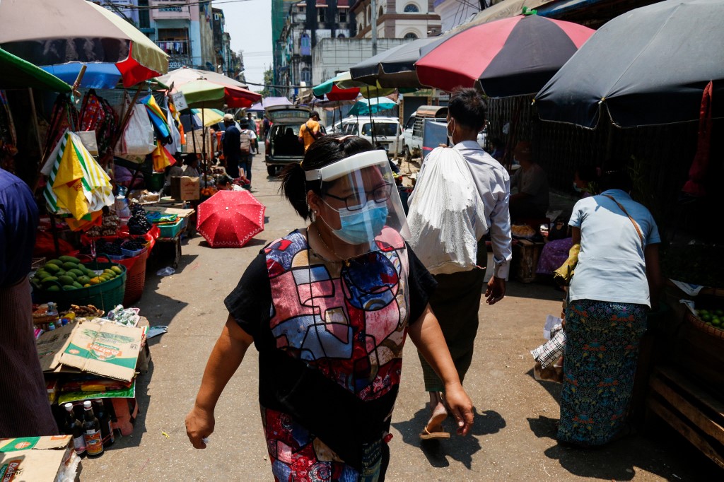  A woman, wears a face shield as a preventive measure against the spread of the COVID-19 novel coronavirus, walks through a street market in Yangon on April 21, 2020. (Sai Aung Main / AFP)