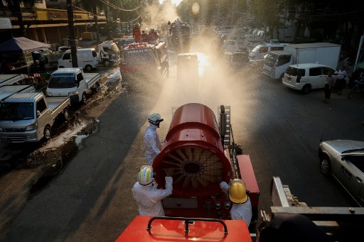 Firefighters wearing protective clothing spray disinfectant along a street as a preventive measure against the spread of the COVID-19 novel coronavirus in Yangon on April 23, 2020. (Sai Aung Main / AFP)