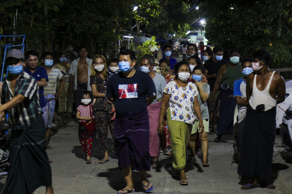 People watch firefighters spraying disinfectant along a street as a preventive measure against the spread of the COVID-19 coronavirus in Yangon on April 24, 2020. (Sai Aung Main / AFP)