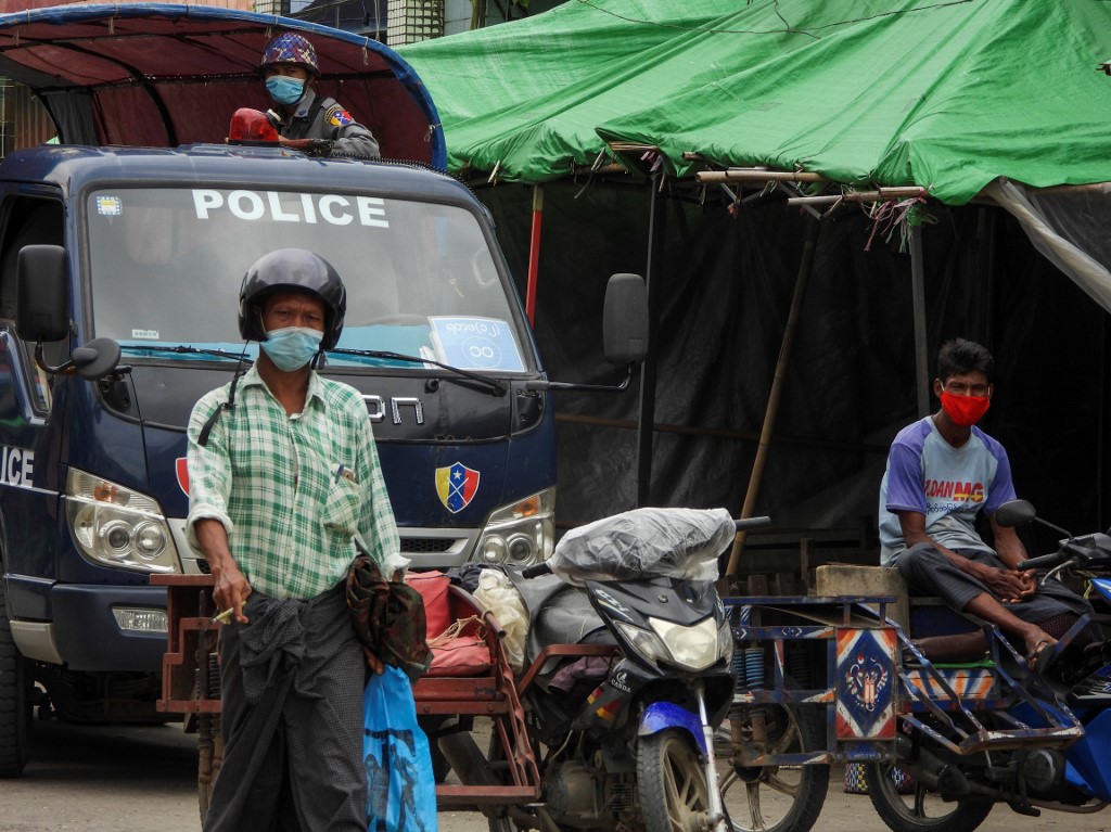 A police watches over from a vehicle while people wear face masks on a street on August 23, 2020 during a lockdown amid fears of the Covid-19 coronavirus in Sittwe. (AFP)