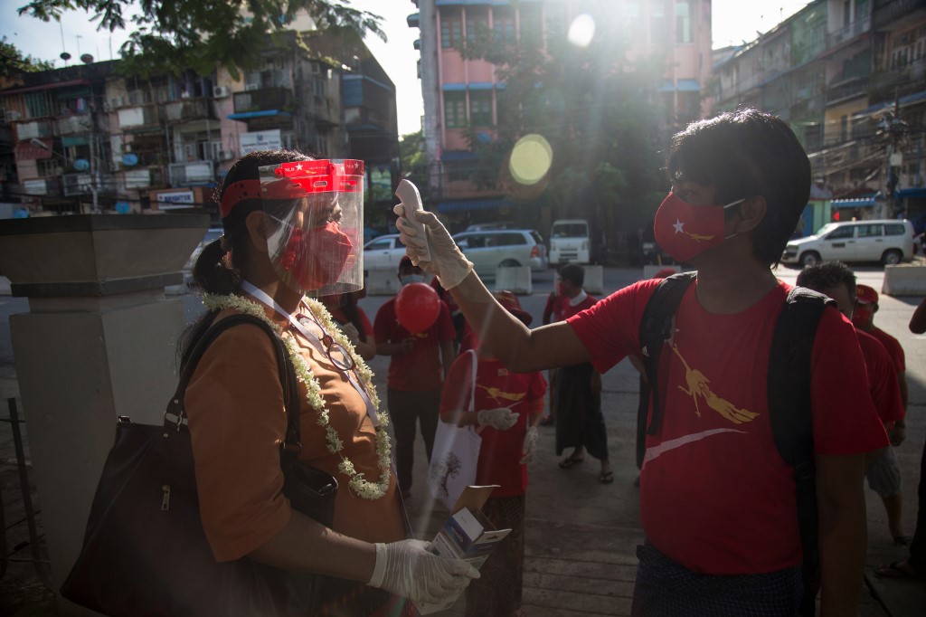 A National League for Democracy supporter checks the temperature for a fellow activist as they launch the campaign for the upcoming November 8 general election in Yangon on September 8, 2020. (Sai Aung Main / AFP)