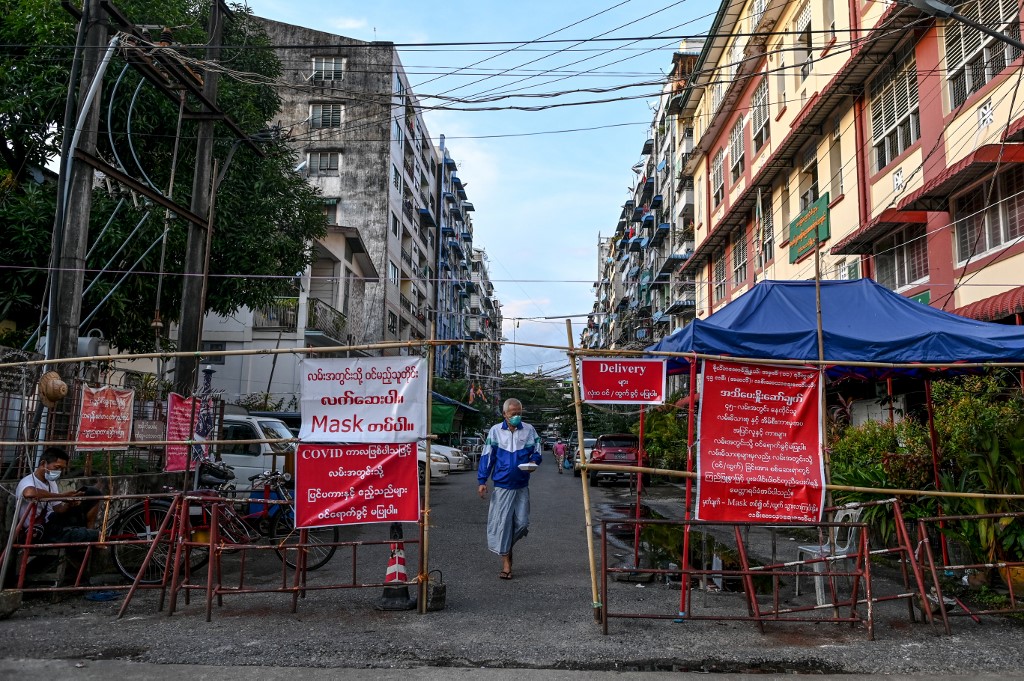  A man walks past a barrier blocking access to minor roads next to a sign recommending to residents to stay at home in Yangon on September 26, 2020, as new restrictions have been introduced to try to halt a surge in Covid-19 coronavirus cases. (Ye Aung Thu / AFP)