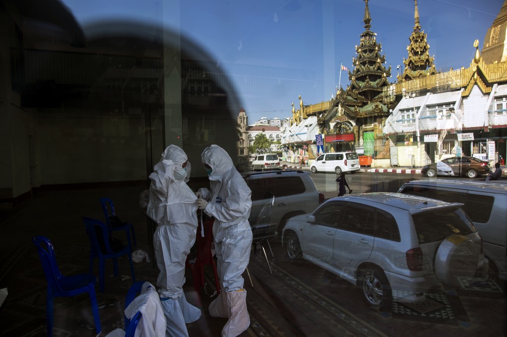 Medical personnel prepare personal protective equipment (PPE) before conducting medical test for domestic airline passengers at the Covid-19 coronavirus rapid diagnostic testing centre in central Yangon ahead of their scheduled travel on December 21, 2020. (Sai Aung Main / AFP)