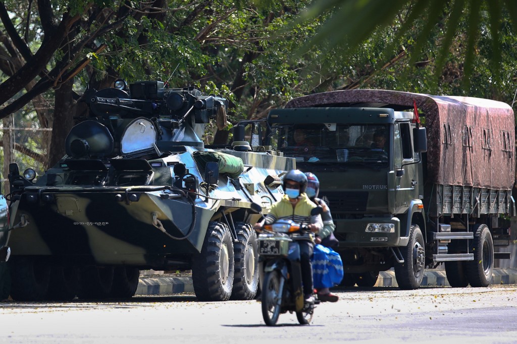 Motorists pass military vehicles near a guesthouse, where members of parliament reside, in the country's capital Naypyidaw on February 3, 2021, as Myanmar's ousted leader Aung San Suu Kyi was formally charged on Wednesday two days after she was detained in a military coup. (STR / AFP)
