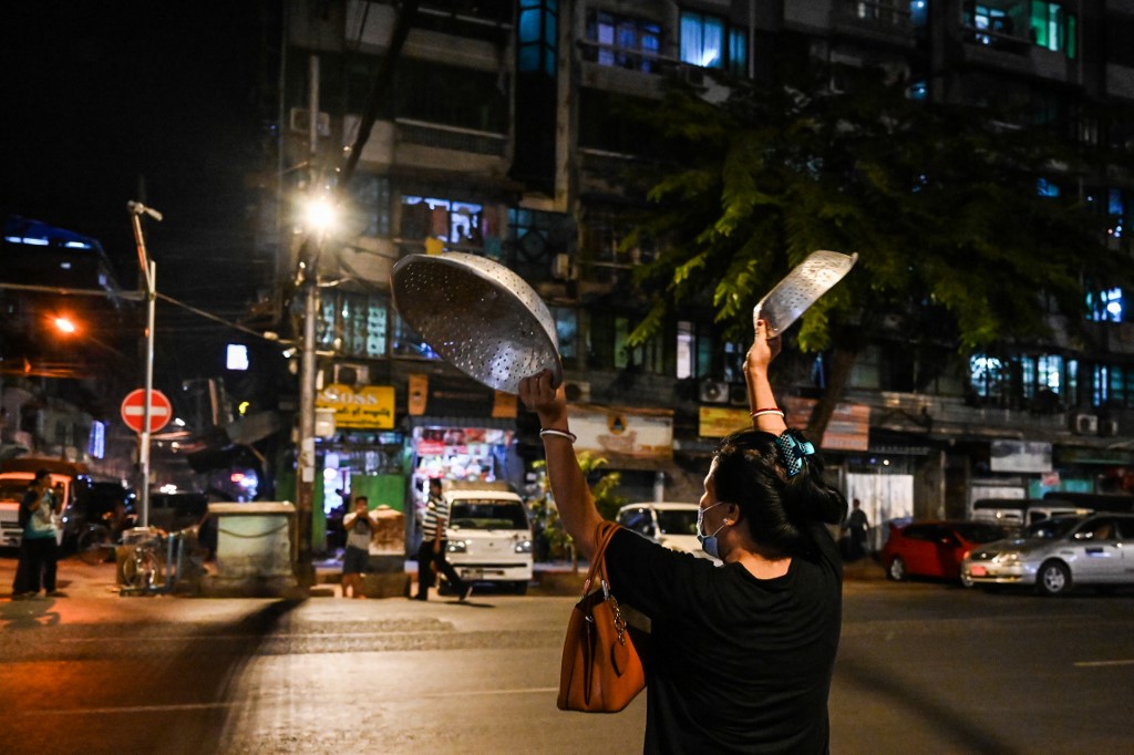 A woman clatters pans to make noise after calls for protest went out on social media in Yangon on February 3, 2021, as Myanmar's ousted leader Aung San Suu Kyi was formally charged on Wednesday two days after she was detained in a military coup. (STR / AFP)