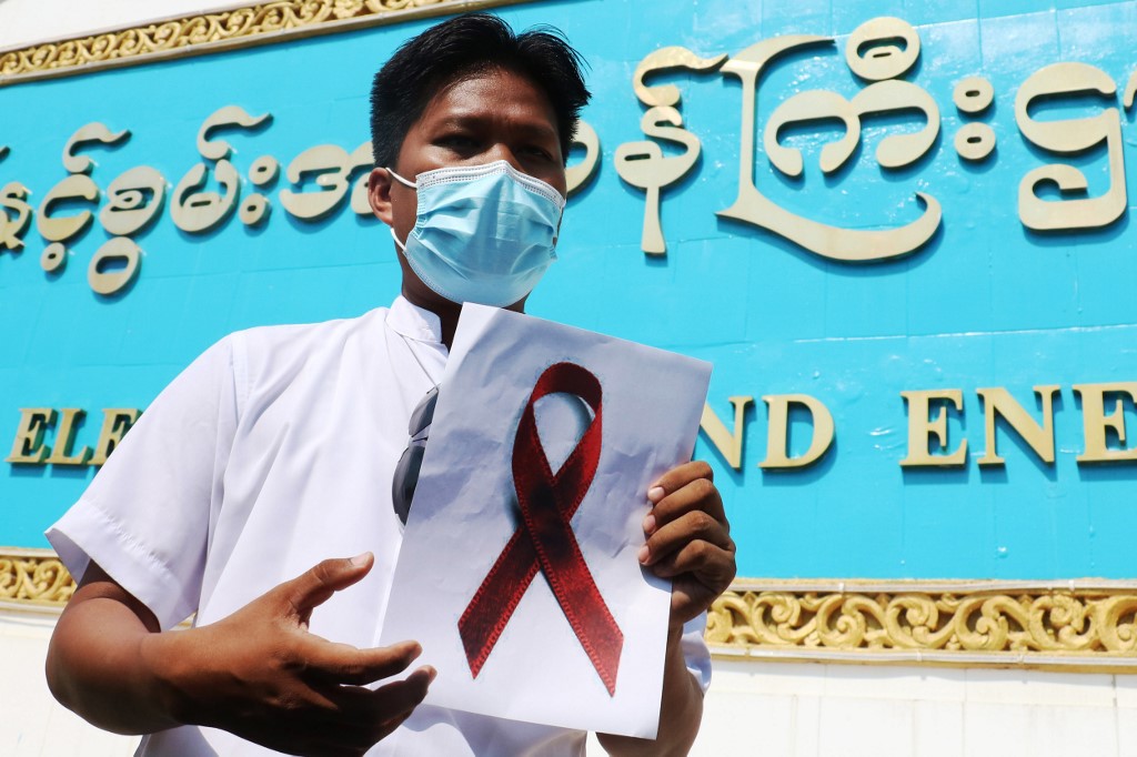 A staff member of the Ministry of Electricity and Energy holds a sign with a red ribbon during a protest against the military coup in Naypyidaw on February 5, 2021. (STR / AFP)