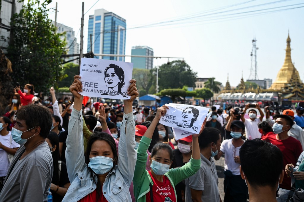 Protesters hold signs with the image of detained civilian leader Aung San Suu Kyi on a street during a demonstration against the military coup near Sule Pagoda in Yangon on February 7, 2021. (Ye Aung Thu / AFP)