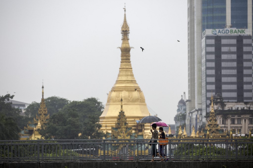 A woman (right) wears a face mask whilst walking with a friend past Sule Pagoda in Yangon on July 26, 2017. (Aung Kyaw Htet / AFP)