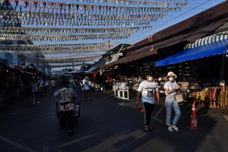 People in face masks walk through an unusually empty Chatuchak weekend market in Bangkok, on March 21, 2020. (AFP)