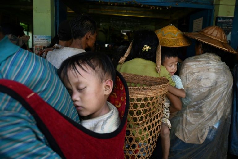 Children being carried as people, affected by clashes between the military and ethnic rebel groups, wait to receive supplies from local civil society organisations in Man Lwal village, outside Kutkai in Shan state. (Ye Aung Thu / AFP)