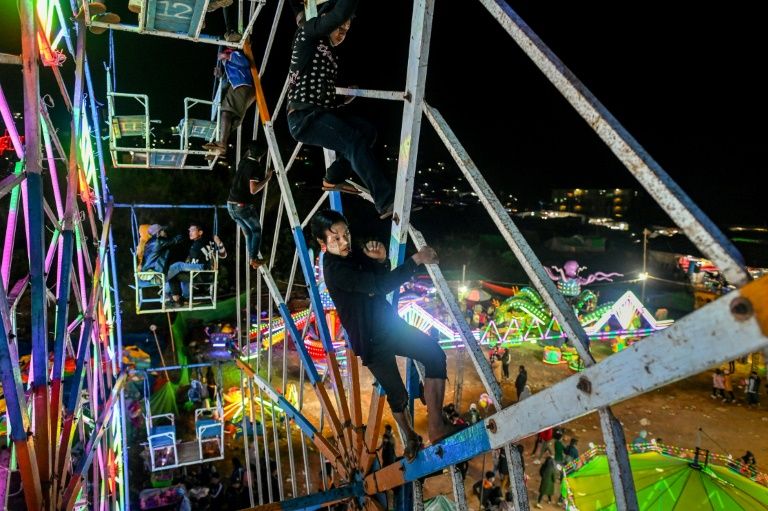 This photo taken on November 6, 2019 shows Aung Sein Phyo (C), 22, and other crew members operating a human-powered ferris wheel in Taunggyi, Shan state. (Ye Aung Thu / AFP)