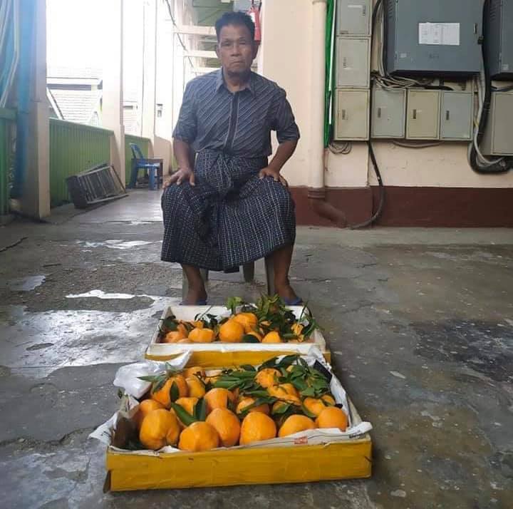 Fruit vendor Thein Tun sits in front of his oranges at Bogyoke Aung San Market in Yangon. (Facebook)