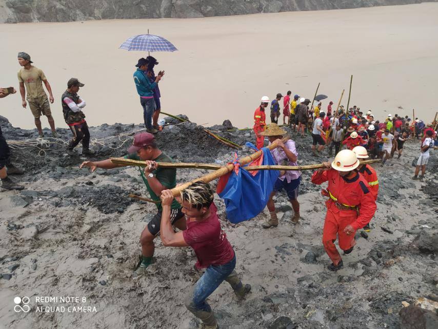 Rescuers carry the body of a jade miner pulled from the mud after a landslide in Kachin state. (Myanmar Fire Services Department / Facebook)