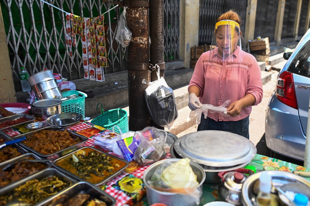 A street food vendor wears a face shield as a preventive measure against the spread of the COVID-19 novel coronavirus in Yangon on April 12, 2020. (Ye Aung Thu / AFP)