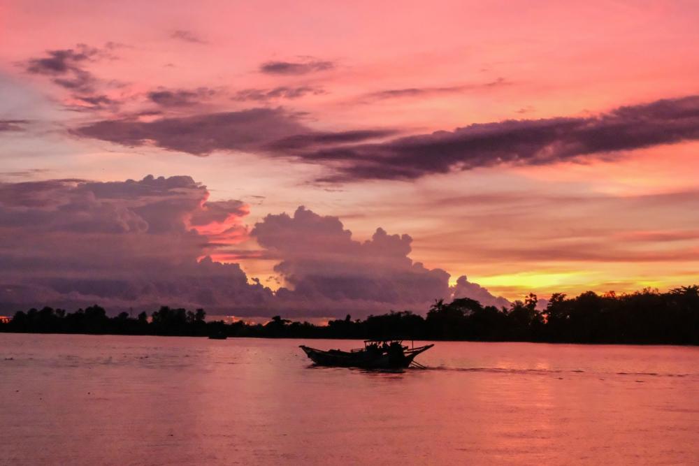 A sunset over Twante Canal turns the sky caramel pink as passengers enjoy cocktails on the back deck of the Moken Treasure. (Marie Starr)