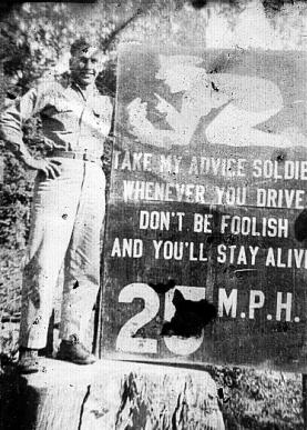 A soldier stands beside a "stay alive" sign.