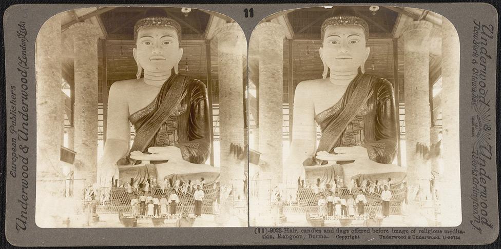 Hair, candles and flags offered before image of religious meditation in Rangoon.