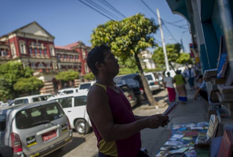 A book seller arranges books at his sidewalk bookshop along Pansodan Street in Yangon. (Ye Aung Thu / AFP)