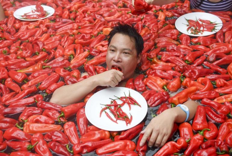  A competitor taking part in a chilli pepper eating contest in a hot spring filled with chilli peppers. (STR / AFP)