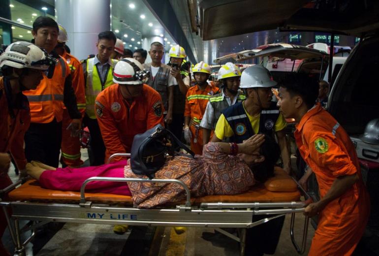  Rescue workers transport an injury passenger on a stretcher after a passenger aircraft of Biman Bangladesh airlines slipped off a runway at Yangon International airport on May 8. (Myo Kyaw Soe / AFP)