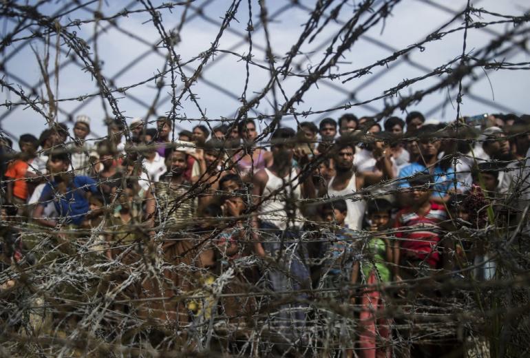   In this file photo taken on April 25, 2018, taken from Maungdaw district, Myanmar's Rakhine state on April 25, 2018 shows Rohingya refugees gathering behind a barbed-wire fence in a temporary settlement setup in a "no man's land" border zone between Myanmar and Bangladesh. (Ye Aung Thu / AFP)