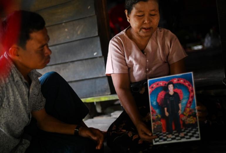 This photo taken on October 2, 2019 shows Phyu Shwe Nu, the mother of Zaw Lin who is currently on death row in Thailand for the alleged murder of two young British tourists, displaying a photo of her son during an interview in her home in Michaung Yaythauk, a village only accessible by boat in Myanmar's western Rakhine state. (Ye Aung Thu / AFP)