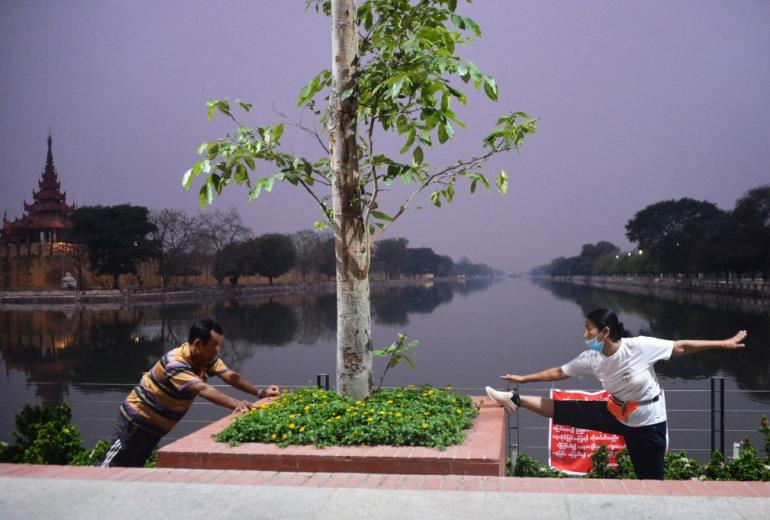 People wearing face masks exercise at dawn in Mandalay on April 7, 2020, as the regional government started a community lockdown to combat the spread of the COVID-19 novel coronavirus. (Thet Aung / AFP)