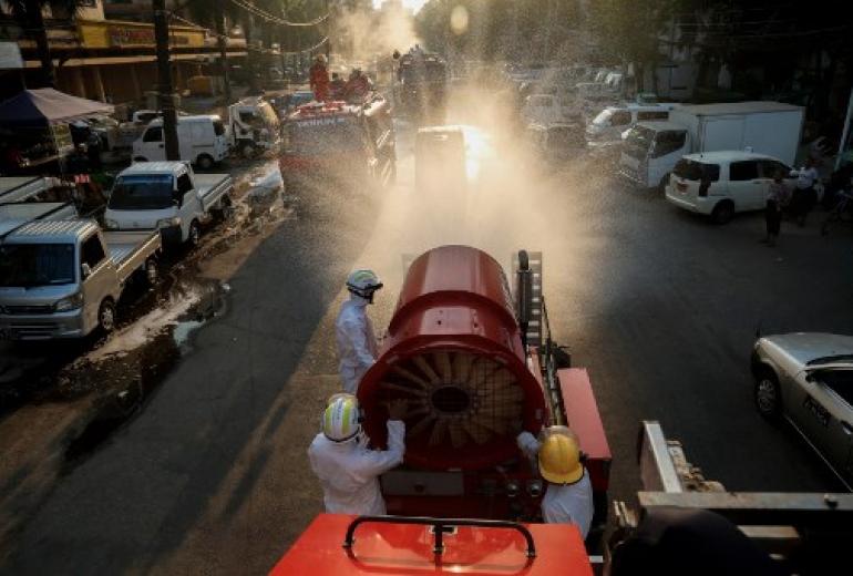 Firefighters wearing protective clothing spray disinfectant along a street as a preventive measure against the spread of the COVID-19 novel coronavirus in Yangon on April 23, 2020. (Sai Aung Main / AFP)