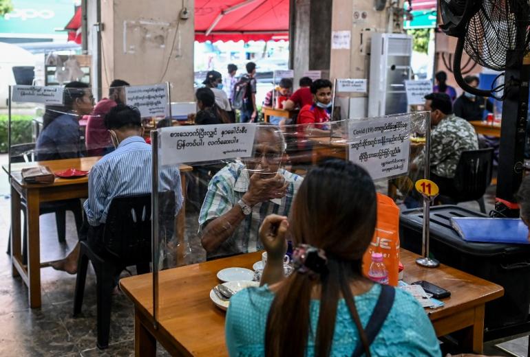    People sit at tables with plastic dividers, as a preventive measure against the spread of the COVID-19 coronavirus, at a restaurant in Yangon on May 26, 2020. (Ye Aung Thu / AFP)