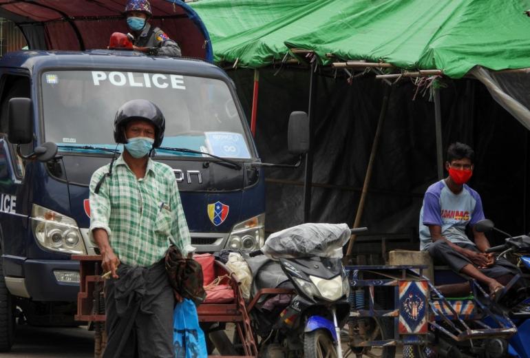 A police watches over from a vehicle while people wear face masks on a street on August 23, 2020 during a lockdown amid fears of the Covid-19 coronavirus in Sittwe. (AFP)