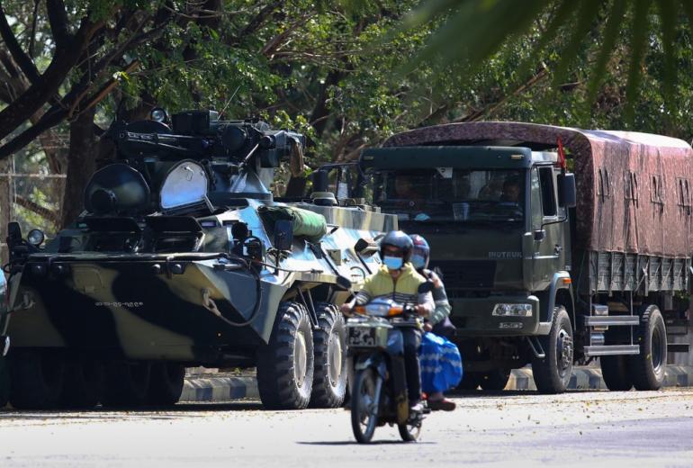 Motorists pass military vehicles near a guesthouse, where members of parliament reside, in the country's capital Naypyidaw on February 3, 2021, as Myanmar's ousted leader Aung San Suu Kyi was formally charged on Wednesday two days after she was detained in a military coup. (STR / AFP)