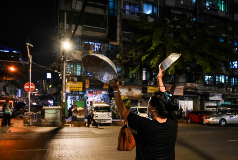 A woman clatters pans to make noise after calls for protest went out on social media in Yangon on February 3, 2021, as Myanmar's ousted leader Aung San Suu Kyi was formally charged on Wednesday two days after she was detained in a military coup. (STR / AFP)