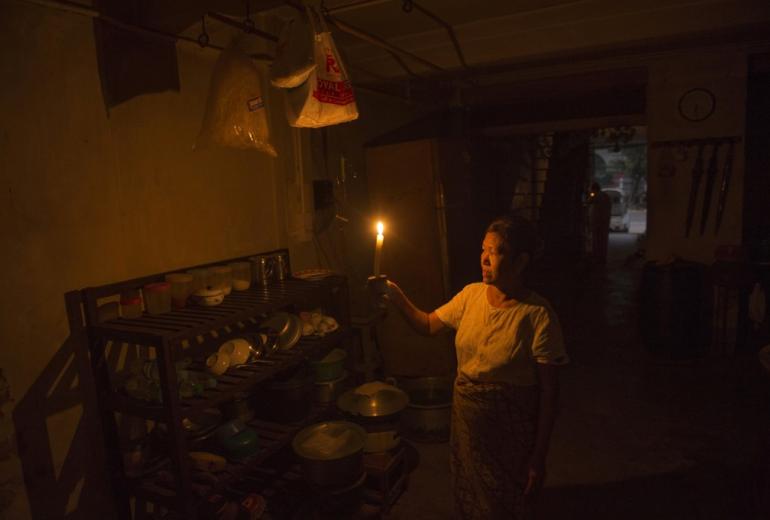 A Yangon resident lights a candle after a power outage in her apartment on Merchant Street. (Romeo Gacad/AFP)