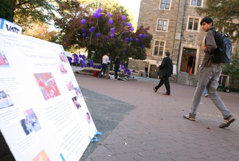  This photos from 2010 shows a Georgetown University student looks at the poster that encourages students to vote in a mock election of Burma as he walks by on campus. (AFP)