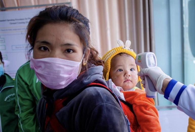 A Myanmar health officer checks the temperature of a child entering the Myanmar-China border crossing checkpoint in Muse, Shan State on January 31, 2020. (Phyo Maung Maung / AFP)