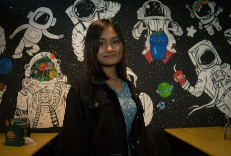 Thet Thet Soe, 19, poses in front of one of her wall paintings at Mario Juice and Snack Bar in Loikaw. (Yan Naing Aung)