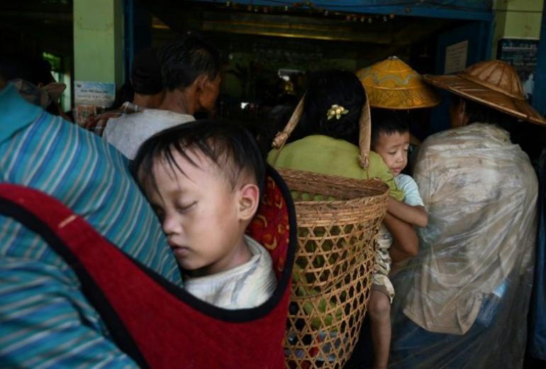 Children being carried as people, affected by clashes between the military and ethnic rebel groups, wait to receive supplies from local civil society organisations in Man Lwal village, outside Kutkai in Shan state. (Ye Aung Thu / AFP)