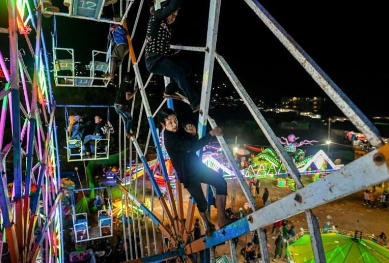 This photo taken on November 6, 2019 shows Aung Sein Phyo (C), 22, and other crew members operating a human-powered ferris wheel in Taunggyi, Shan state. (Ye Aung Thu / AFP)