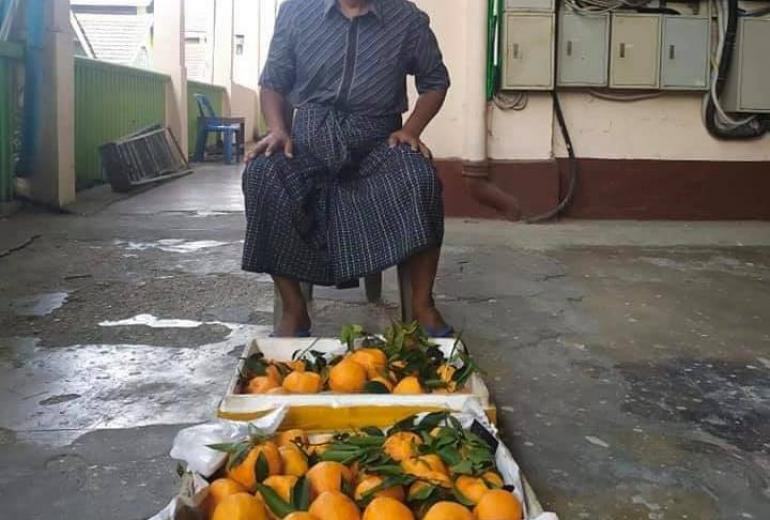 Fruit vendor Thein Tun sits in front of his oranges at Bogyoke Aung San Market in Yangon. (Facebook)