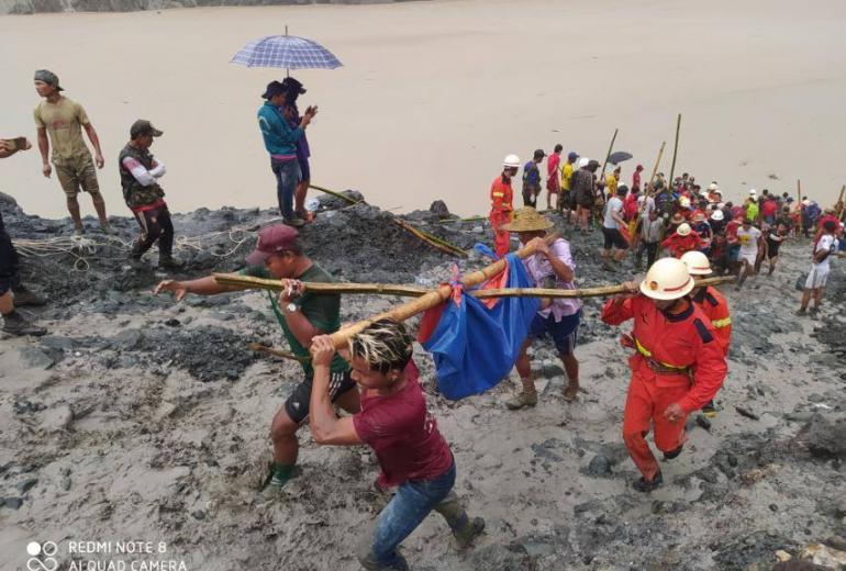 Rescuers carry the body of a jade miner pulled from the mud after a landslide in Kachin state. (Myanmar Fire Services Department / Facebook)