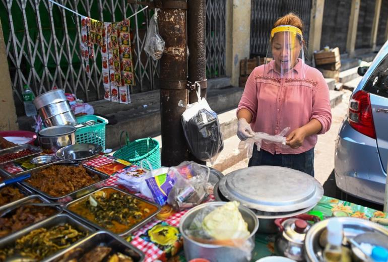 A street food vendor wears a face shield as a preventive measure against the spread of the COVID-19 novel coronavirus in Yangon on April 12, 2020. (Ye Aung Thu / AFP)